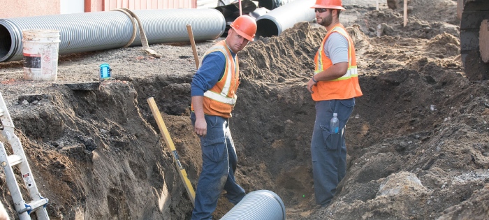 Crew laying underground utility pipe in an open trench